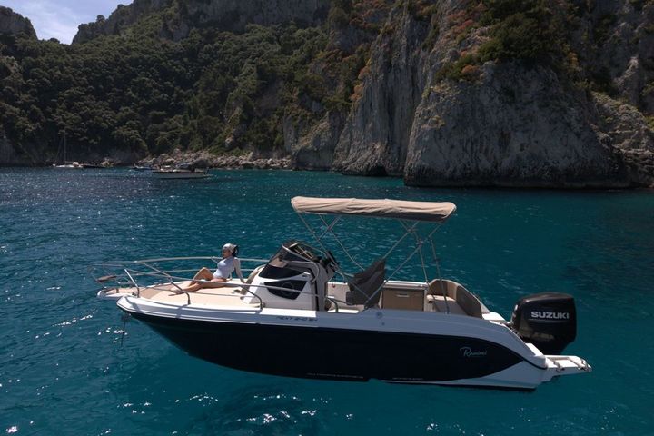 A guest sunbathing on the bow of a private boat in a quiet bay