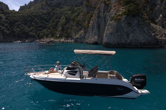 Un'ospite prende il sole a prua di una barca privata in una baia tranquilla